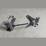 Dvojpedál na bicí buben s kovovým konstrukcí v stříbrné a modré barvě. Na obou šlapkách je viditelný nápis DIXON. Pedál vykazuje známky používání v p…