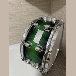 Zelený buben s glitrovým povrchem a chromovaným kováním. Na korpusu je kovový štítek s nápisy „Sultuap“, „MAPEX“ a „Custom Series“. Na horním obruči…