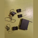 Sada černého bezdrátového systému skládající se z jednoho vysílače, dvou přijímačů a napájecího adaptéru. Na přístrojích je vidět logo s písmenem S a…