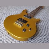 Zlatá elektrická kytara s dvojcutovým tvarem těla a hnědým hmatníkem. Nástroj je vybaven dvěma černými humbuckery, stříbrným mostem a třemi ovládacím…