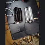 Dvě černé humbucker snímače s bílými plastovými krytkami nad pólky. Snímače jsou vybaveny připojovacími kabely a kovovými montážnímideskami. Na povrc…