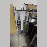 Dvě kovové stoličky nebo stojany stříbrné barvy s černou vodorovnou horní deskou. Konstrukce jsou opatřeny žluto-černými varovnými pruhy a spodní čás…