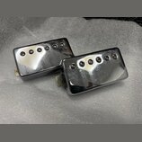 Dvě elektrické kytarové snímače typu humbucker s chromovaným kovovým krytem. Každý snímač má na povrchu šest viditelných polótek. Povrch krytů vykazu…