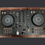 Černý DJ kontrolér s dvěma jog-koly a centrálním mixážním sekcí. Na přístroji jsou viditelné nápisy PERFORMANCE DJ CONTROLLER, DDJ-FLX4, rekordbox a…