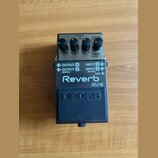 Efektový pedál Reverb značky BOSS, model RV-5. Zařízení je v černém kovovém provedení s šedým horním panelem, na kterém jsou čtyři ovládací knoflíky…