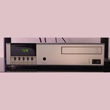 Stříbrný audio komponent s digitálním displejem, na kterém svítí zelený nápis AM 7.28. Na pravé straně je logo v kruhu a nápis LINN, v dolní části je…