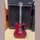 Červená elektrická kytara s černým pickguardem a dvěma humbuckery. Na hlavě hmatníku je nápis Epiphone. Kytara má typický SG tvar těla, čtyři ovládac…