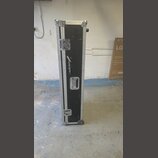 Černý transportní kufr s hliníkovými hranami a kovovým kováním. Na přední straně je svisle umístěné bílé logo a nápis audio-technica. Povrch kufrů vy…