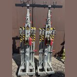 Na fotografii jsou dva identické kovové vozíky s mechanismem navijáku a červenými páky. Konstrukce je z galvanizované oceli s žluto-černými varovnými…