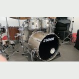 Sada bubnů značky SONOR v béžové barvě s kovovým kováním. Na předním koži basového bubnu je bílý nápis SONOR s logem. Sestava obsahuje basový buben,…