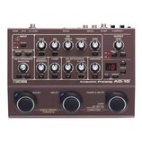 Hnědý kytarový předzesilovač s nápisy BOSS a Acoustic Preamp AD-10. Zařízení obsahuje řadu ovládacích potenciometrů, přepínačů a červené digitální di…