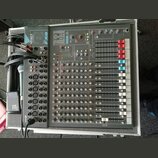 Šedý míchací pult s nápisy SPIRIT a FX8 umístěný v transportním kufru. Zařízení obsahuje řadu regulačních potenciometrů, posuvníků a vstupních konekt…