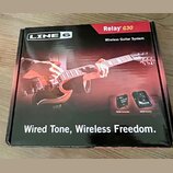 Kartonová krabice s nápisy LINE 6, Relay G30 a Wireless Guitar System. Na povrchu je fotografie rukou hrajících na červenou elektrickou kytaru a obrá…