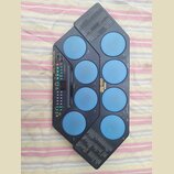Elektronický bicí pad modré barvy s černým plastovým rámem. Na přístroji je nápis YAMAHA a model DD-12, dále text Super Session Pad / Player / Scrape…