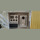 V bílém kartónovém boxu jsou dvě stříbrná zařízení. Levý pedál má nápisy BEATBUDDY a Singular Sound, horní ovládací panel s displejem a popisky Volum…