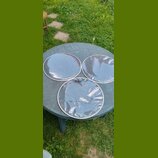 Tři průhledné plastové bubny s bílým okrajem položené na kulatém zeleném stole. Na jednom z bubnů je viditelné modré logo s nápisem EVANS. Povrchy js…
