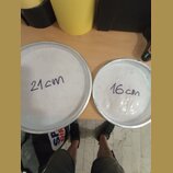 Dvě bílé bubnové membrány v kovových obručích. Na levé, větší membráně je ručně napsáno „21cm“ a na pravé, menší membráně „16cm“. Povrchy jsou bílé a…