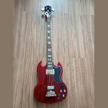 Červená elektrická basová kytara s tmavým hmatníkem a černým pickguardem. Na hlavě je bílý nápis Epiphone. Nástroj má dva snímače a čtyři ovládací kn…