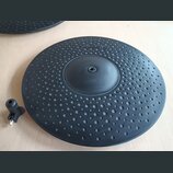 Černý gumový pad elektronického činely s povrchem pokrytým drobnými důlky. V horní části je vyražen nápis ALESIS. Vlevo je vidět připojovací kabel s…