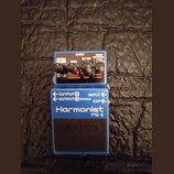 Modrý efekt pedál s nápisy Harmonist a PS-6. Na horní části jsou čtyři ovládací knoflíky, červená kontrolka CHECK a přepínače s popisky BALANCE, SHIF…