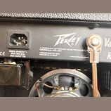 Detail zadní strany kytarového komba s černým povrchem. Je zde vidět napájecí konektor a bílý nápis Peavey s textem A PRODUCT OF PEAVEY ELECTRONICS C…