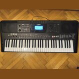 Černý digitální klavír s bílými a černými klávesami. Na horní části je logo YAMAHA, displej s nápisem BrandPro a vpravo označení modelu PSR-E463. Nás…