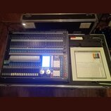 Světelný kontrolér v transportním kufru. Na zařízení je nápis LIGHT CONTROLLER a logo Avolites s označením TITAN. Ovládací panel obsahuje velké množs…