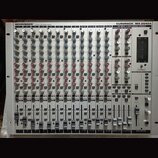 Stříbrný míchací pult s nápisy BEHRINGER® ULTRA-LOW NOISE DESIGN a EURORACK MX 2642A 26 INPUT 4-BUS MIXING CONSOLE. Zařízení obsahuje řady šedých, mo…