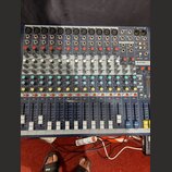 Modrý mixovací pult s kovovým šasi a řadou vertikálních posuvníků. V pravém horním rohu je nápis Soundcraft a dále modelové označení EPM12. Zařízení…