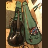 Tmavě hnědá housle v otevřeném černém kufru s zeleným vnitřkem. Vedle nástroje leží smyčec a modré balení strun s nápisy "Alice", "VIOLIN STRINGS" a…