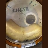 Fotografie zachycuje bílý plastový bubenový kožen s nápisem AMATE a logem značky EVANS, pod kterým je uveden text MADE IN USA. Pod koženem je umístěn…