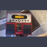 Červený vokální procesor značky BOSS s nápisy VE-20 VOCAL PROCESSOR a Vocal Performer. Zařízení má stříbrný ovládací panel s displejem, na kterém je…