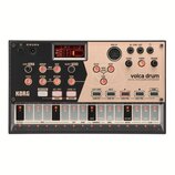 Digitální perkusní syntetizátor volca drum značky KORG v béžovo-stříbrném provedení. Zařízení obsahuje displej s červeným textem LAY 1-2, řadu ovláda…