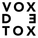 Fotografie zobrazuje černý nápis na bílém pozadí. Text je rozdělen do tří řádů a tvoří slova VOX, D E a TOX. Písmo je bezpatkové, tučné a v horním re…