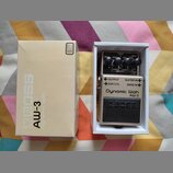 Krabice a efekt pedál značky BOSS model AW-3 Dynamic Wah. Pedál je umístěn v bílé krabičce a má stříbrné tělo s černým spínacím pedálem, na kterém je…