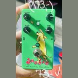 Zelený kytarový efekt s nápisy OUTPUT, GAIN, BLEND a TONE u ovládacích knoflíků. Uprostřed je bílé tlačítko s nápisem SCOOP a obrázek žlutého psa. Ve…