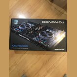 Kartonová krabice s obrázkem černého DJ kontroléru. Na krabici jsou nápisy DENON DJ, MC4000 a PREMIUM 2-CHANNEL DJ CONTROLLER. V pravém dolním rohu j…