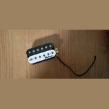 Černý humbucker s bílým plastovým krytem. Na krytu je černý nápis jackson. Snímač má připojení v podobě černého kabelu a vykazuje mírné znečištění po…