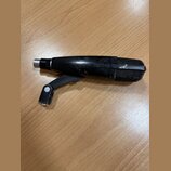 Černý mikrofon s mřížkou a připevněným držákem, položený na dřevěném povrchu. Tělo mikrofonu vykazuje viditelné známky opotřebení v podobě odřesů a š…