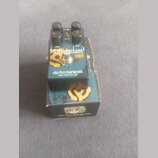 Kytarový efekt pedál značky electro-harmonix v černé barvě s modro-žlutým grafickým motivem. Na horní straně jsou tři černé ovládací knoflíky a nápis…