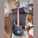 Černá elektrická kytara s dvojcutem a černým hardwarem. Na hlavě hmatníku je bílý nápis Cort. Kytara má dva humbuckery, jeden potenciometr a jeden př…