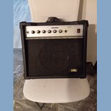 Černý kytarový kombo zesilovač s bílým ovládacím panelem a černou textilní maskou reproduktoru. Na panelu je nápis GUITAR AMPLIFIER, model AK30A a na…