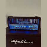 Kytarový zesilovač značky Hughes & Kettner, model TubeMeister 18. Přední panel je vybaven ovládacími knoflíky pro Treble, Mid, Bass, Master Gain a Cl…