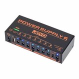 Černý napájecí adaptér s oranžovými nápisy POWER SUPPLY 5 a logem JOYO. Zařízení má na přední straně USB port, osm výstupů pro DC konektory a několik…