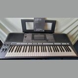Tmavě šedý digitální klavír značky YAMAHA. Na ovládacím panelu jsou tlačítka,točítka a displej; nad klávesami je nápis STYLE CONTROL. V hudebním stoj…