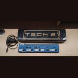 Na fotografii je modrý kytarový efektový pedál s nápisy BASS FLY RIG a TECH 21. Na přístroji jsou vidět ovládací knoflíky, přepínače a nápisy CHORUS/…