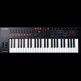 Černý MIDI kontrolér s klávesnicí. Na horním panelu jsou vidět posuvníky, červená tlačítka a sekce s nápisy M-AUDIO, SMART CHORD a OXYGEN PRO 43. V p…