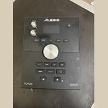 Černý elektronický modul Alesis Forge Advanced Drum Module. Na přední straně jsou dva ovratové knoflíky s nápisy MASTER VOLUME a PHONES, displej, zap…