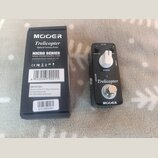Na fotografii je černý efekt pedál Mooer Trelicopter a jeho originální krabička. Na pedálu je nápis Trelicopter, značka MOOER a ovládací prvky s popi…