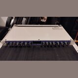 Bíle provedené rackové studio zařízení s modrým předním panelem. Na panelu jsou nápisy EXP / GATE, COMPRESSOR / LIMITER a ENHANCER, doprovázené řadou…